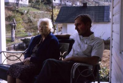 Man and woman sitting on a bench on the porch of a white house