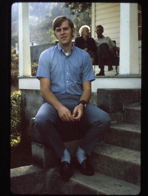 Portrait of Gregory Fields with family on porch in background