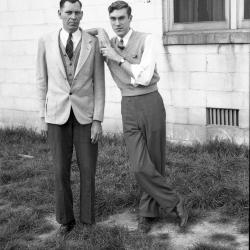 Two men posing in front of a building