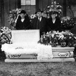 Three people standing with an open casket