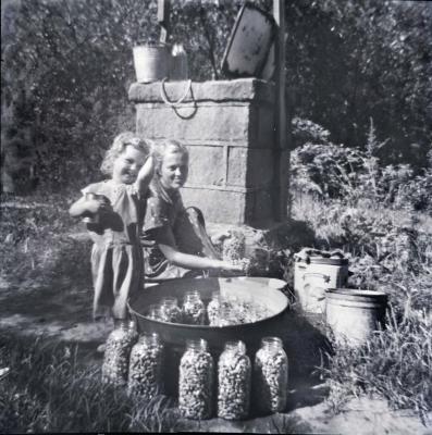 Exterior of woman and daughter canning beans, smiling at camera