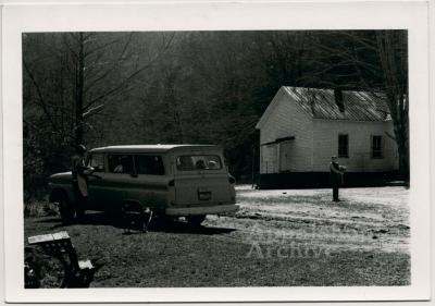 Production still of car and school building - Kingdom Come School