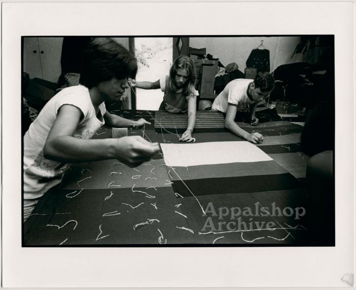 Young people working at quilting frame - Millstone Sewing Center